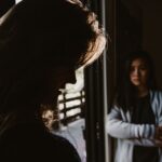 A shadowed woman looks down in regret while another watches, illustrating the struggle between false and true repentance.