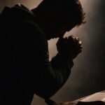 A silhouette of a man praying over a Bible, reflecting the blog's themes of seeking freedom from the crushing weight of shame through spiritual conviction.