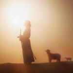 Silhouette of a shepherd holding a staff at sunrise with sheep nearby, symbolizing God’s guidance, protection, and trust in faith.