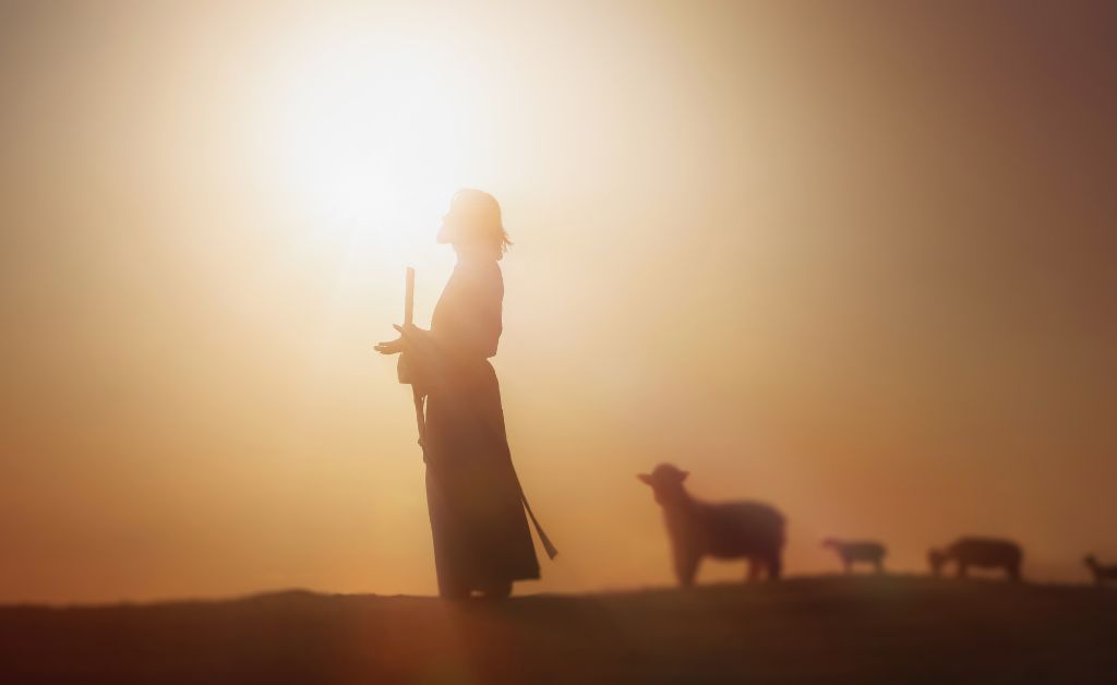Silhouette of a shepherd holding a staff at sunrise with sheep nearby, symbolizing God’s guidance, protection, and trust in faith.